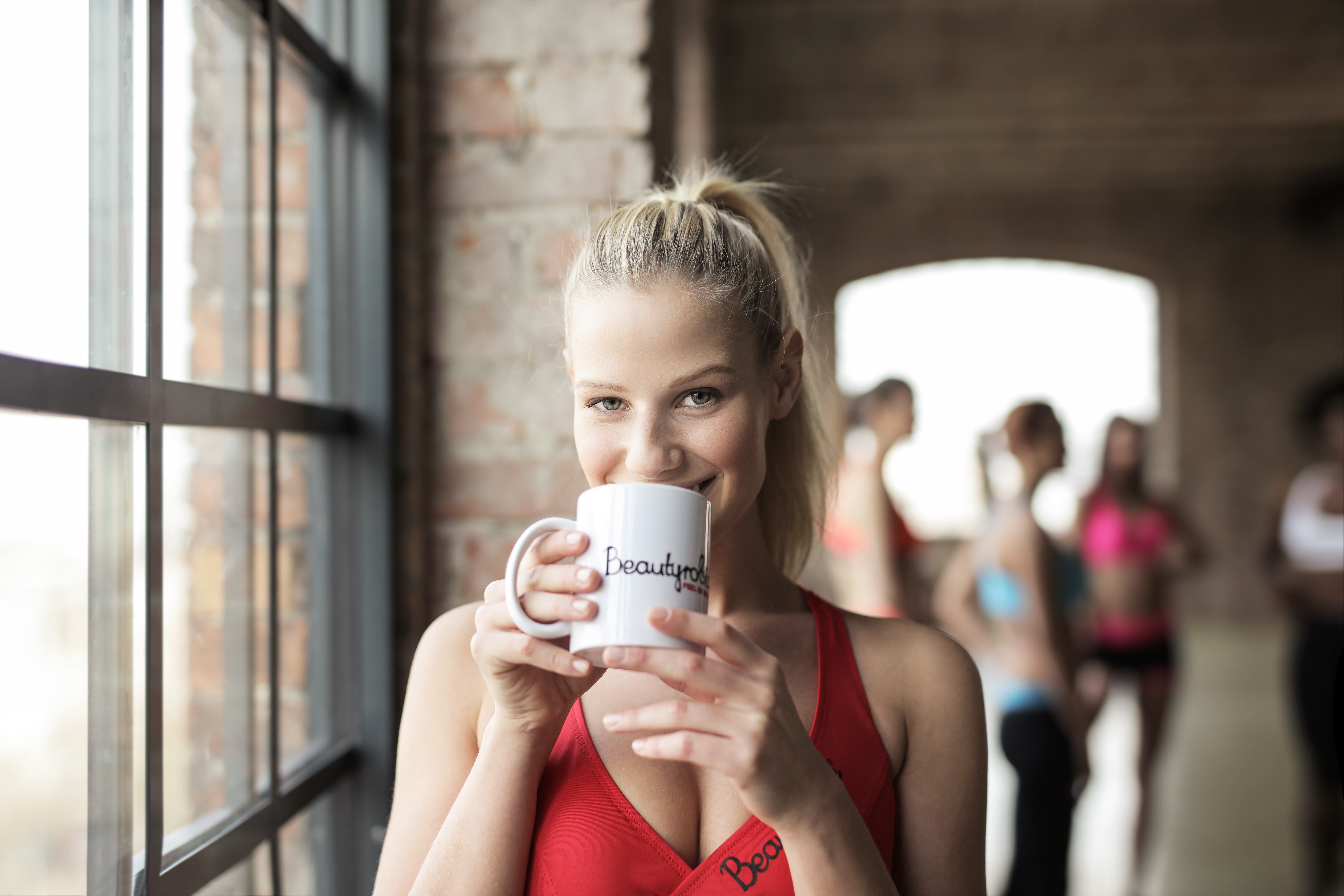 Girl drinking from her gym mug after an intense workout. 