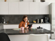 young woman in kitchen leaning on kitchen worktops